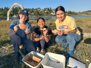 Three volunteers show off their collected crab molts to the camera.