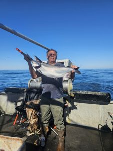 Roger Bain holds up a large salmon onboard his boat