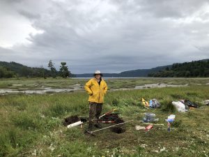 Carrie Garrison-Laney in a marshy field beside equipment used to take sediment cores.