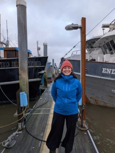 Jess Tantisook stands on a doc between vessels