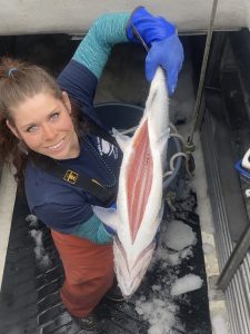 Amy Sharp holds up a fresh-caught salmon with its belly open
