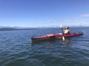 Nicole Fagin in a kayak on the water, mountains looming behind