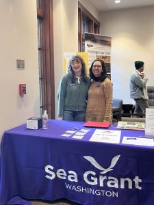 Two smiling people standing behind a Washington Sea Grant table