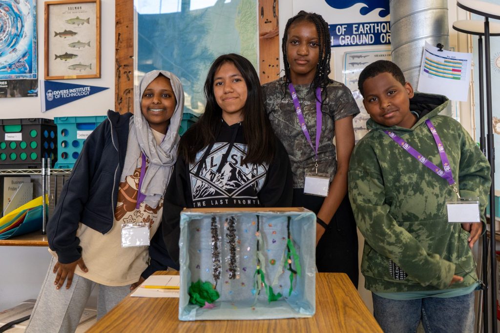 Children stand behind an aquaculture diorama
