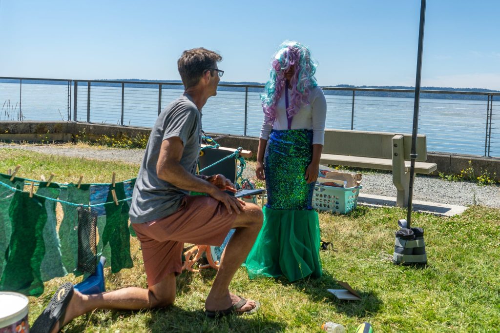 Mike Spranger kneels in front of a child wearing a mermaid costume