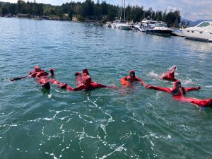Students wearing survival suits in the water