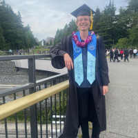 Gabe Diephuis stands in a graduation gown, mortarboard and sash