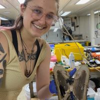 Mel Lemke in a lab holding up a specimen