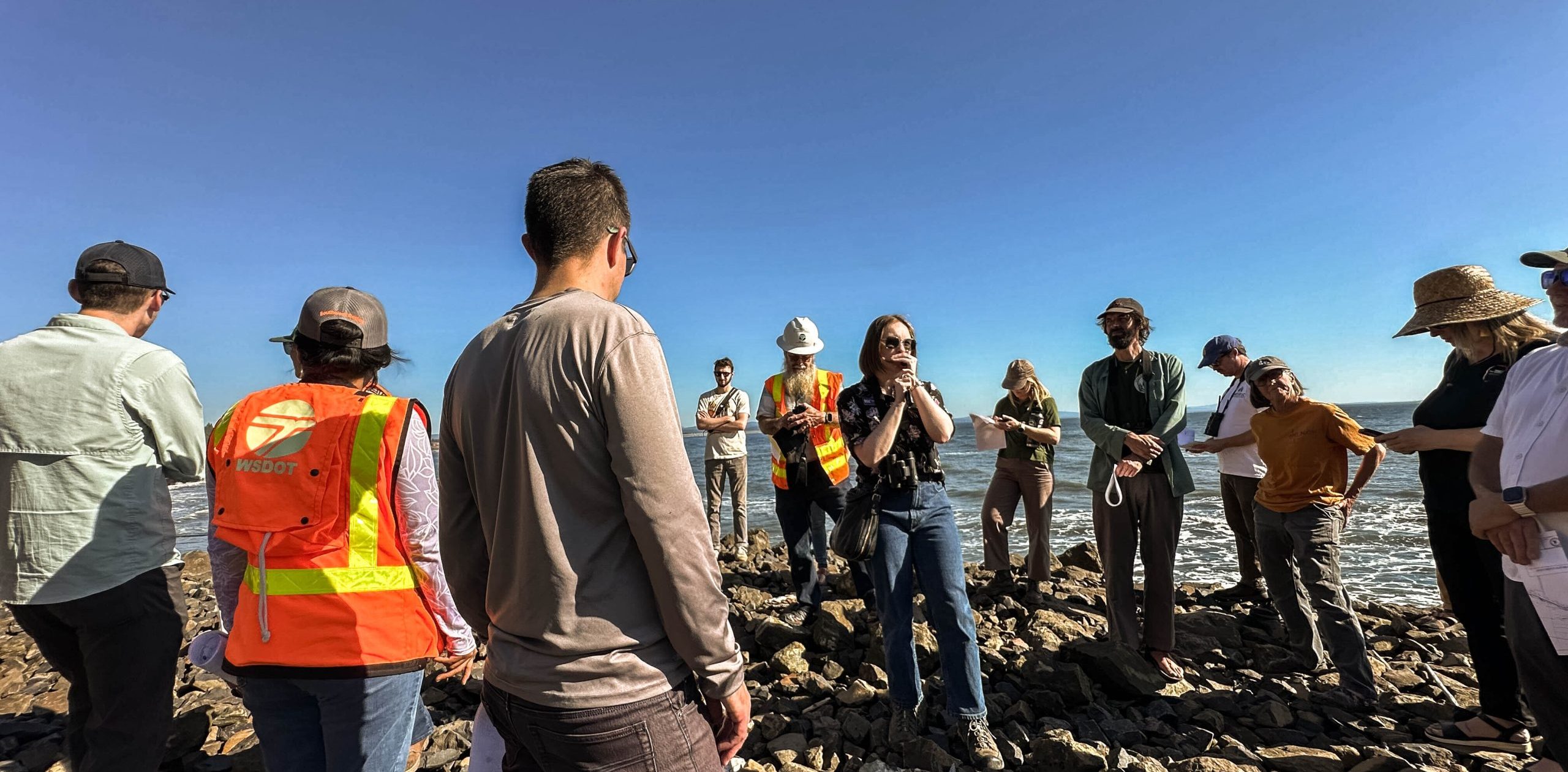 Coastal planners wearing orange vests standing on the shore