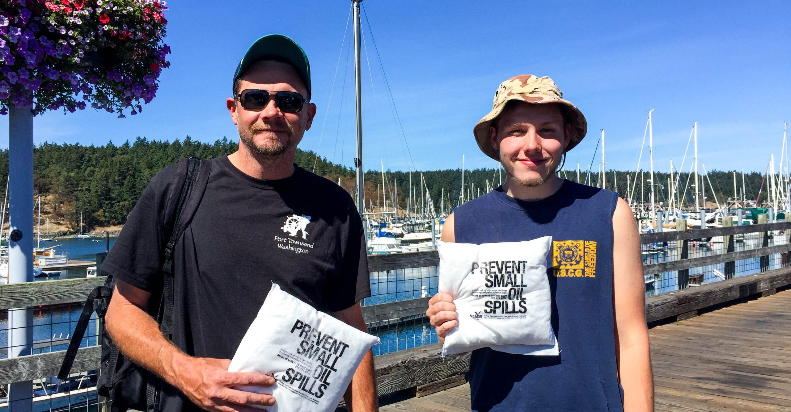 AJ & Shawn holding up their absorbent pads reading "prevent small oil spills"