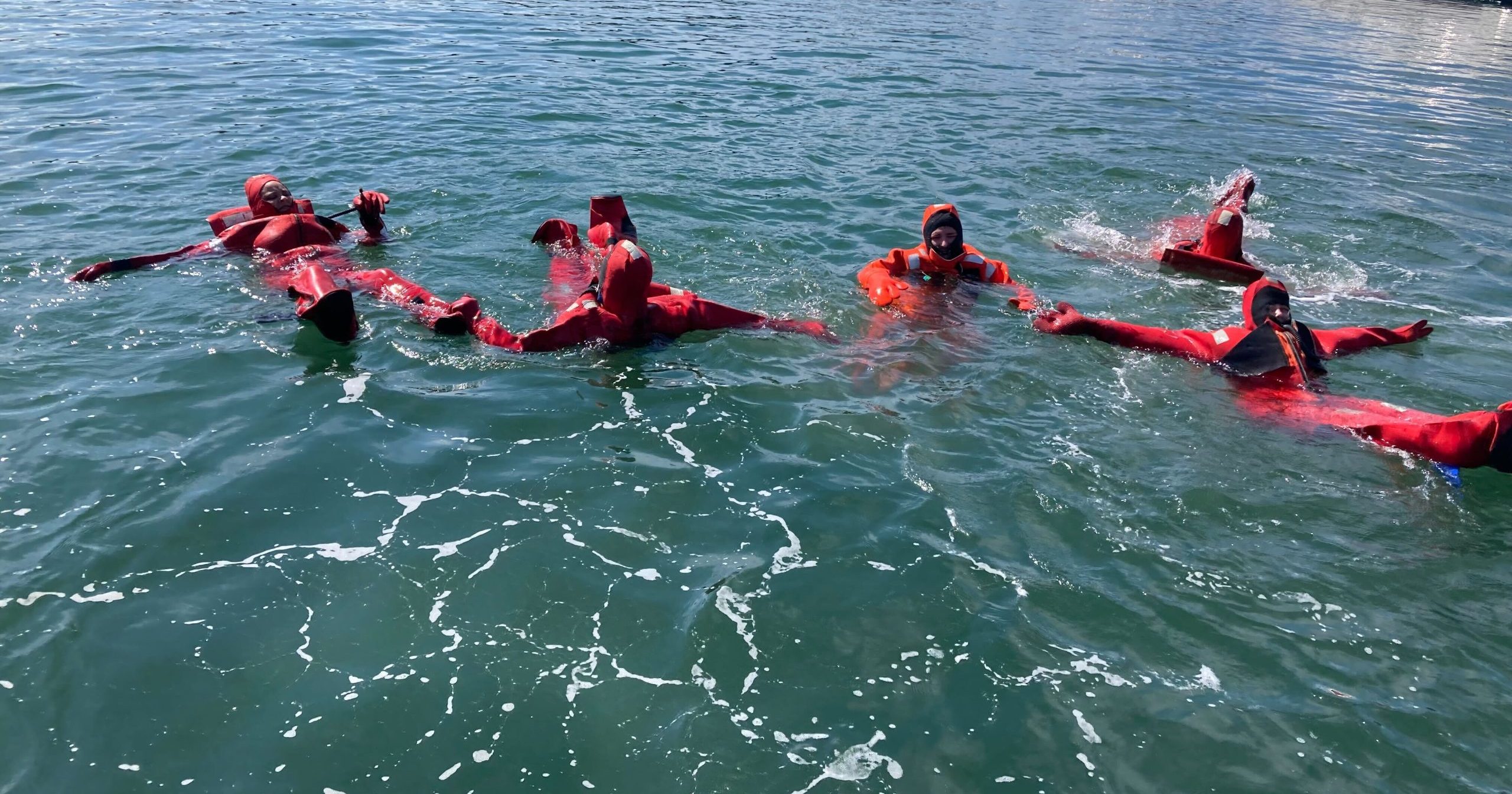 Attendees of a past WSG training wearing survival suits in the water.