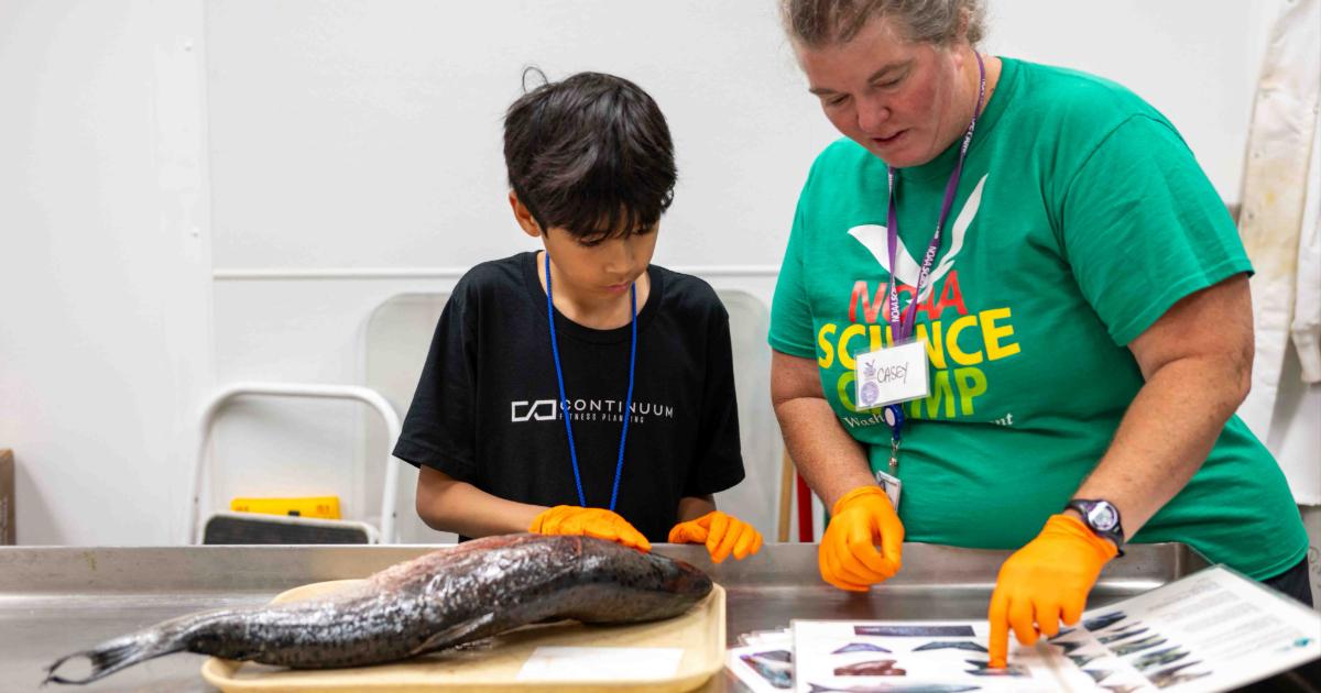 NOAA Science Camp Instructor inspecting a fish with a student