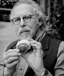 A black and white portrait of David Gordon holding a shell.