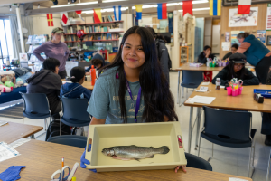 An aquaculture camper shows off a steelhead trout in a scientific tray